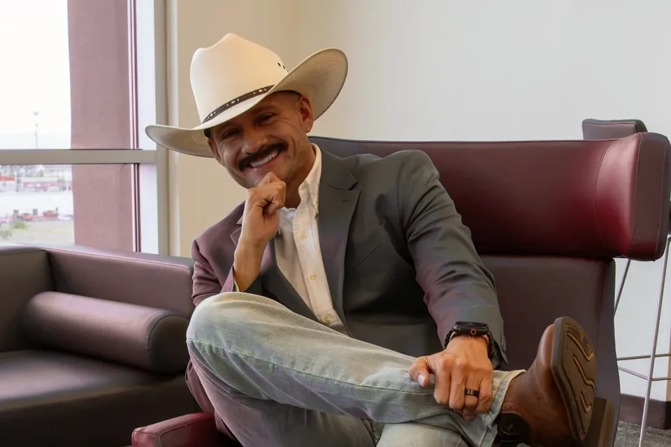 Marcos Ramírez sentado y sonriente en una sala de reunión, listo para conversar